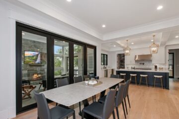 A luxury dining area in front of a large open glass door of a custom modern home, opposite direction.