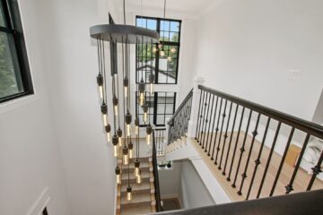 Beautiful modern chandeliers hanging over a staircase in a custom modern home.
