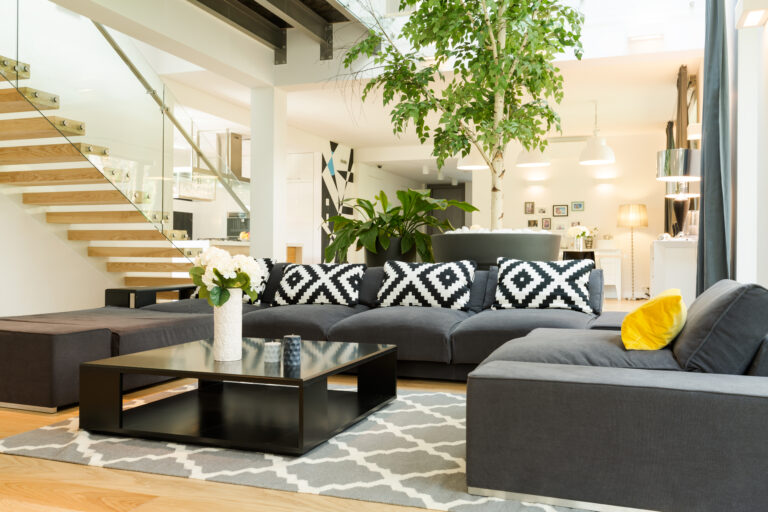 Cozy stylish living room with sofa set and potted plants open to the staircase